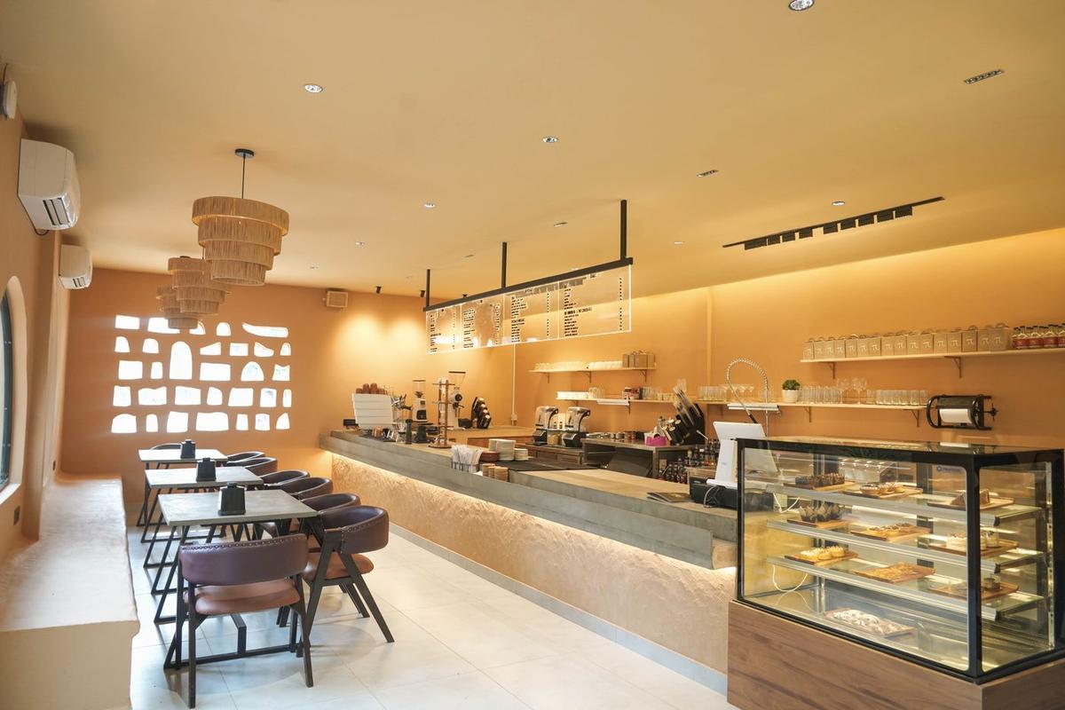 Warm-lit coffee counter with a dessert display