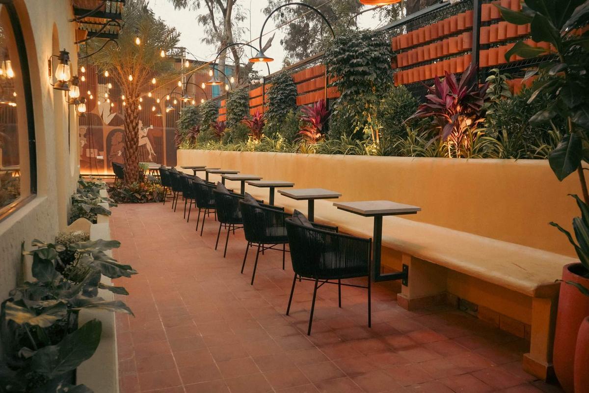 Terracotta courtyard with string lights, plants and long benches at a TAN Coffee outlet