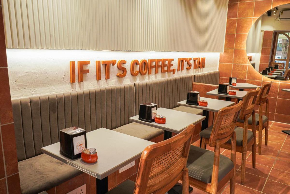 Café seating under the 'If it's coffee, it's TAN' wall sign